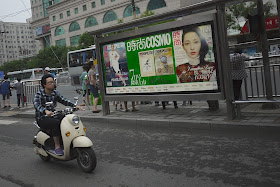 man on motorbike riding by a billboard advertisement for Cosmopolitan magazine