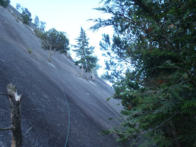 Sara traversing across the face in the crack, trailing the rope behind her uphhill of the trees