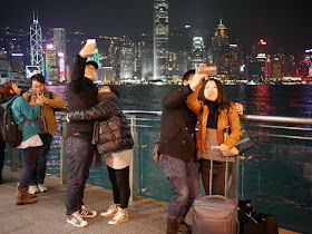 couples taking selfies with the Hong Kong Island skyline in the background