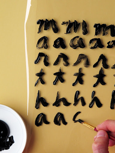 Dip brush in black acrylic paint, and paint on letters or design of your choosing. This will be your film positive.