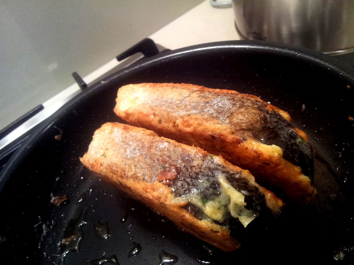 Parmesan crusted salmon frying in the pan on the skin
