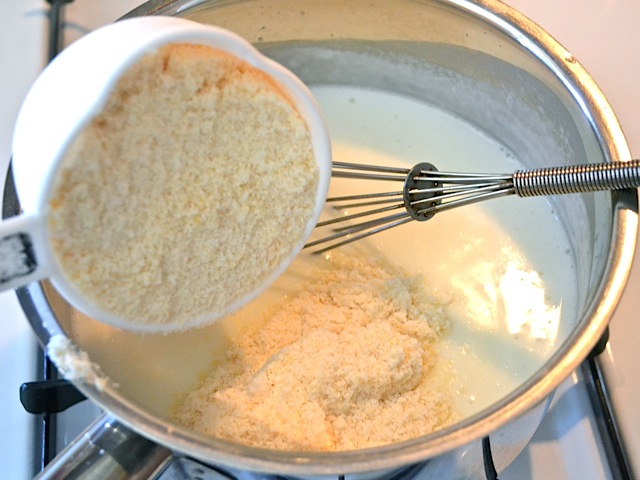 parmesan cheese being added to sauce in pot 