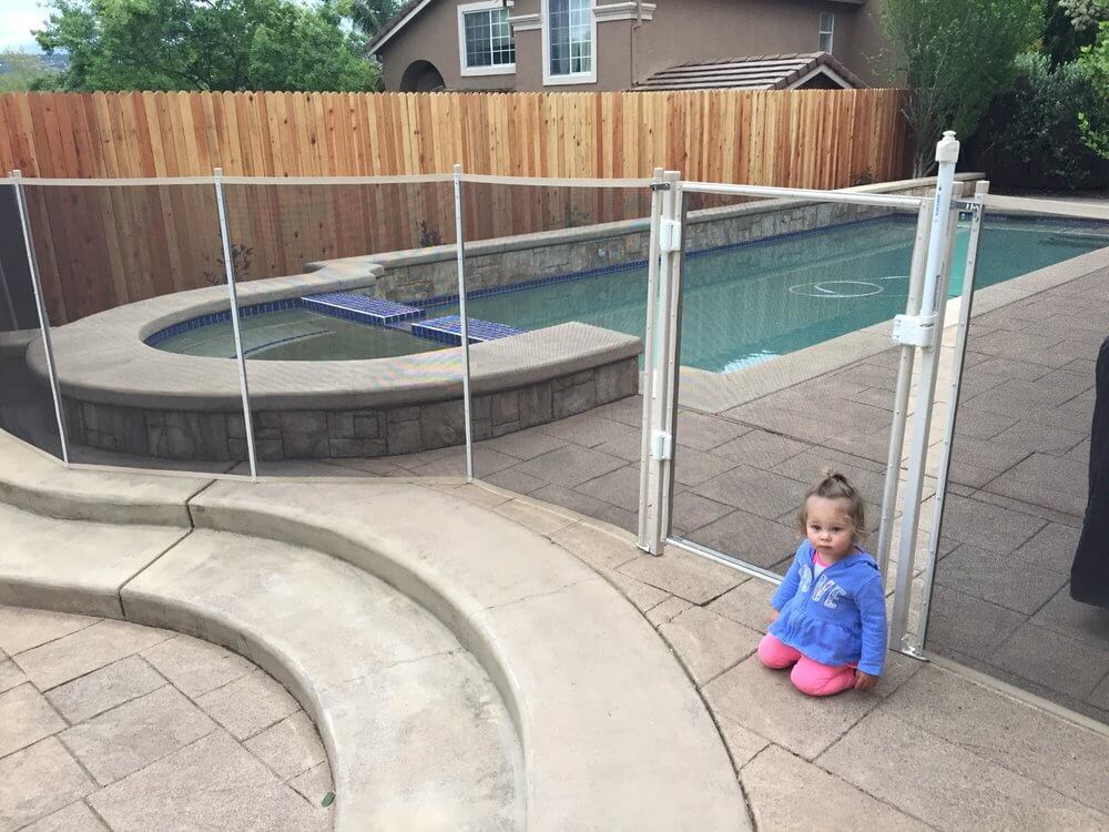 toddler sitting next to a white mesh pool fence