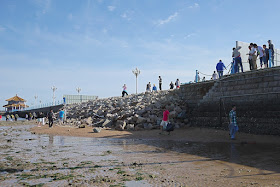 people climbing over a collapsed portion of a pier