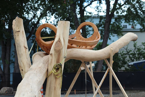 a wooden boat sitting atop a structure made of large, polished tree parts