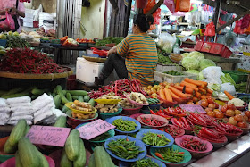 woman sitting next to vegetables for sale at Bazaar Baru Chow Kit in Kuala Lumpur, Malaysia