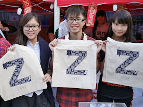 three college students holding bags with a large letter "Z"