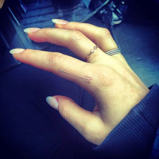 arrow tattoos white ink on her finger