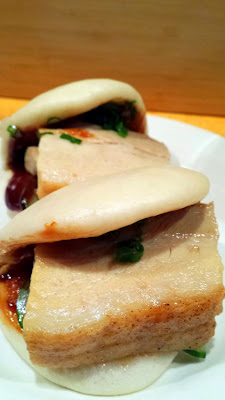 Momofuku Pork Bao- Pork Belly Bun with soft white steamed bun folded around pickled cucumbers and scallions, sweet hoisin and roasted pork belly