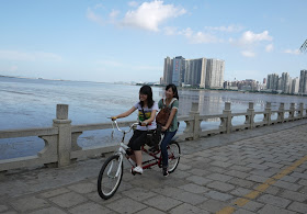 two young women riding a tandem bicycle in Zhuhai, Guangdong province