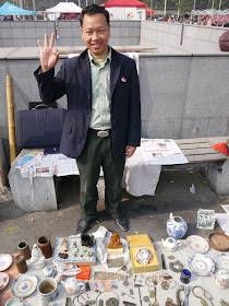 man with his items for sale at an outdoor antique market in Changsha