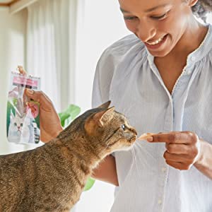 woman feeding cat fillet piece