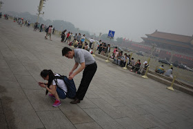 young man checking a young woman's backpack at Tiananmen Square