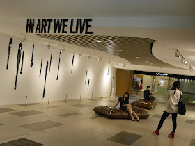 Young woman being photographed in an art installation with the words 'In Art We Live."