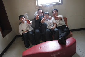 four men smoking while sitting on a small sofa in Changsha, China