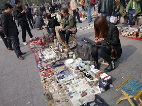 woman looking at her mobile phone at an outdoor antique market in Changsha, China