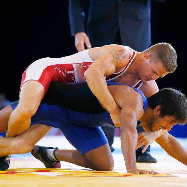 David Tremblay, on top in red, of Canada wrestles Bajrang of India in their men's 61 kg gold medal wrestling bout at the Commonwealth Games Glasgow 2014, in Glasgow, on July 30, 2014.