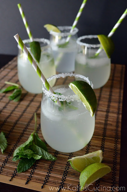 Stemless wine glass with salt and lime on the rim and liquid inside with a striped straw.