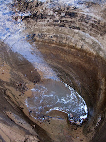 A pothole beginning to fill with water