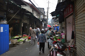 man walking with a cane next to vegetables for sale at Beizheng Street in Changsha, China