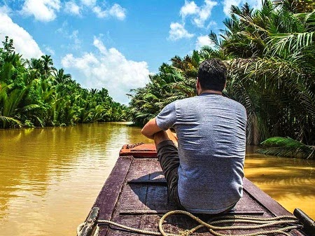 Chris ngồi trên một chiếc xuồng đi thăm thú vùng đồng bằng sông Mekong của Việt Nam.