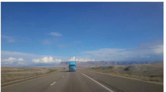 wide shot of a truck on a highway coming towards the camera