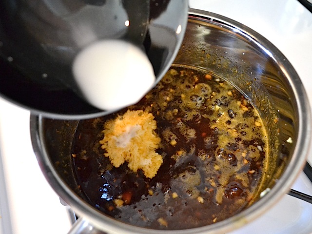 cornstarch being poured into pot to thicken sauce