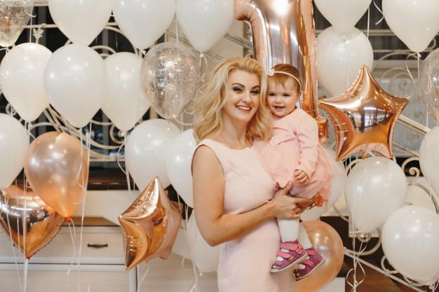Mother holds her cute little daughter on the balloons Free Photo