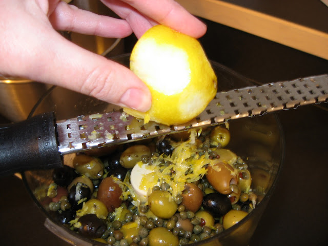 Zesting a Lemon Over Mixed Olives in Food Processor Image