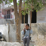 Un petit indien se balance en regardant ses parents travailler