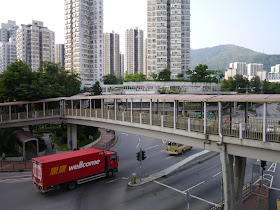 A Wellcome delivery truck passing under an elevated walkway in Tsuen Wan, Hong Kong