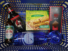 Red Seal Ale, Saranac White IPA, Nature Valley granola bars, 80% dark chocolate, and a bottle of carbonated San Benedetto water in a basket