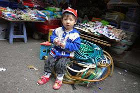 small child sitting on a pile of hoses at a shop in Changsha, China