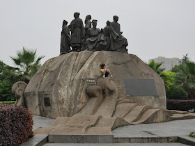 small girl eating ice cream while sitting below statues of Chinese scholars in traditional clothing