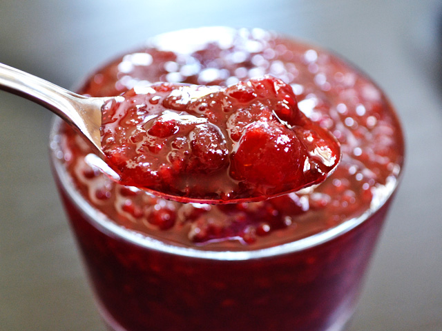 spoonful of jalapeno raspberry cranberry sauce scooped out of glass dish