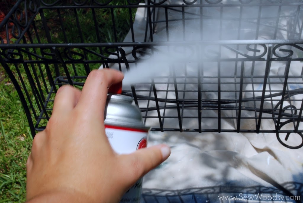 Female hand spraying painting a black basket white.