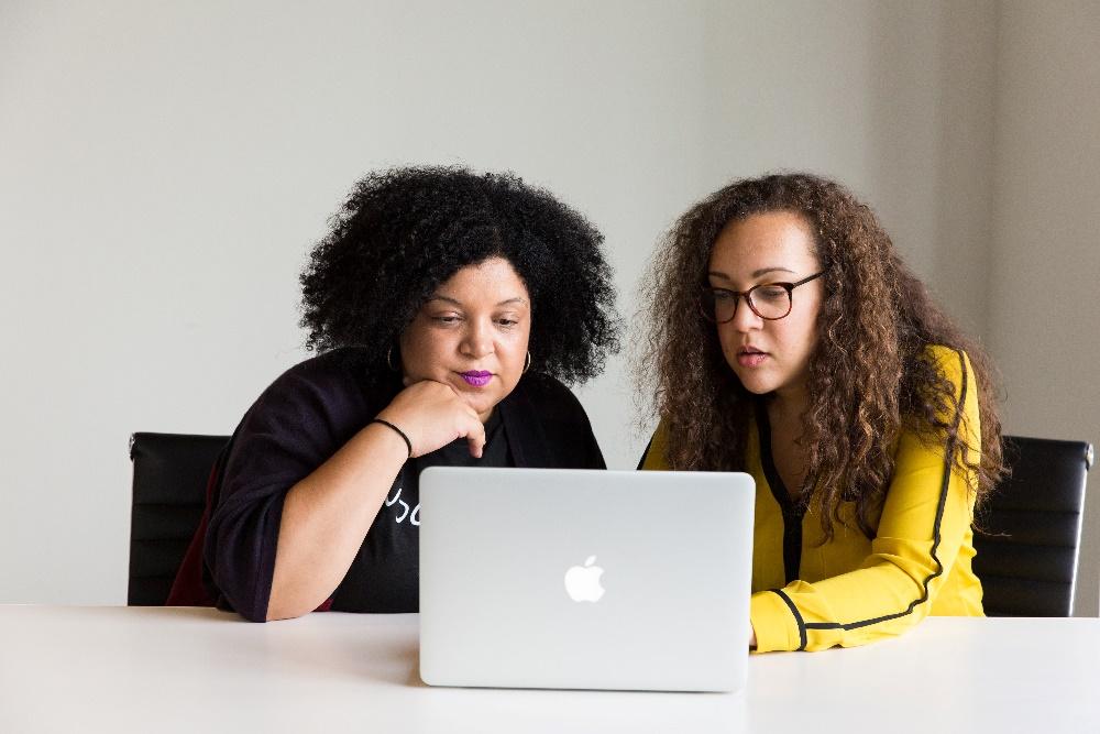 Two women of color looking at a Macbook's screen
