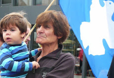 Frau mit Kind auf dem Arm und blaue Friedensfahne mit Taube.