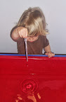 Child uses a pipette to make drops of water.