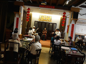 people drinking tea in front of a live traditional Chinese music performance