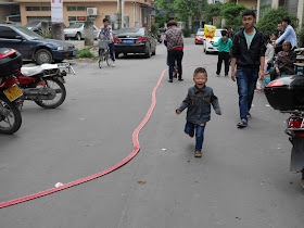 boy excitedly running by a long strip of firecrackers in Maoming, China