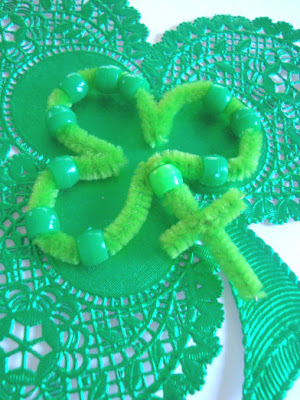 Pipe cleaner shamrock with beads on a shamrock shaped doily
