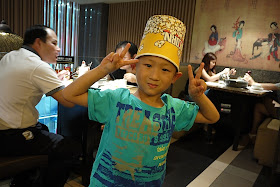 boy wearing a paper popcorn bucket as a hat in Shenzhen, China