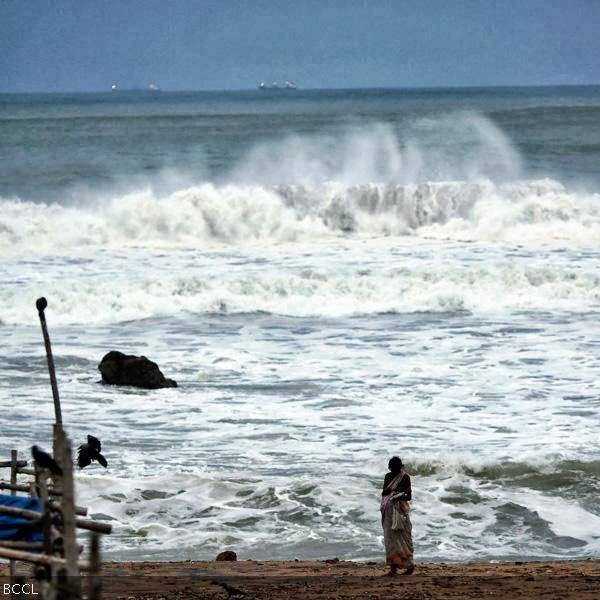 People stand as waves from the Bay of Bengal approach the shore in Visakhapatnam district in the southern Indian state of Andhra Pradesh.