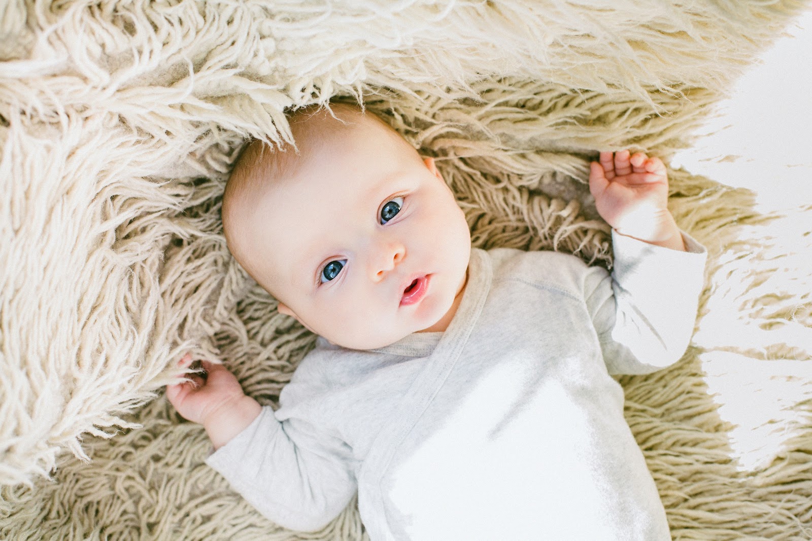 A cute baby laying on a light brown rug
