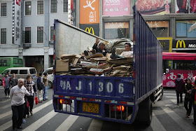 two men lying on cardboard on the back of a truck in Guangzhou, China