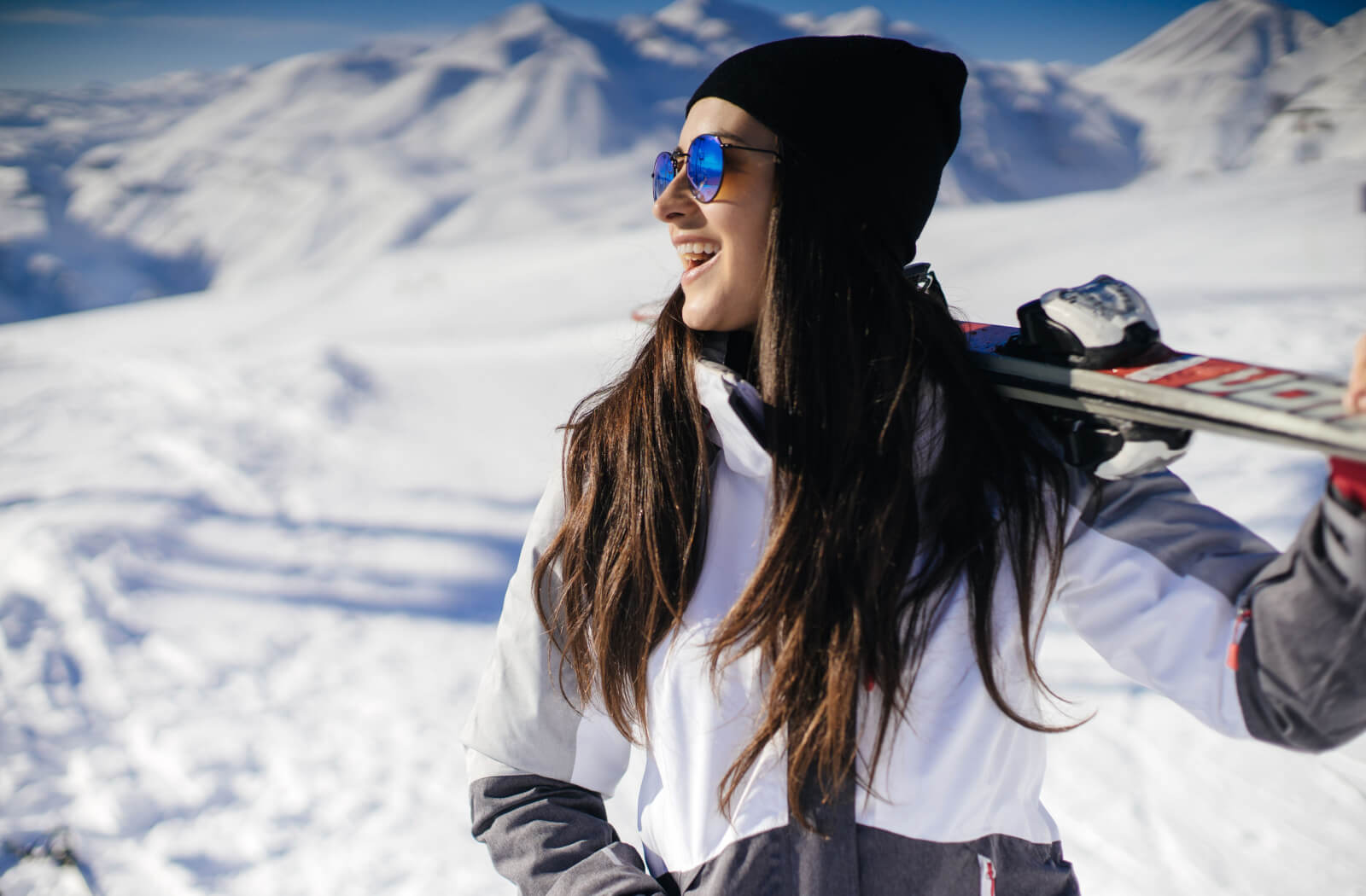 A snowboarder wearing polarized sunglasses looking out at a distance.