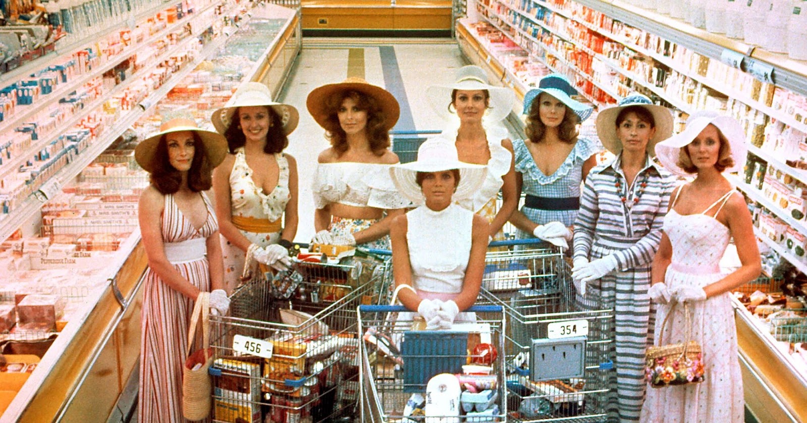 A still from The Stepford Wives. Eight fembots, all dressed like perfect housewives, stand in a grocery store.