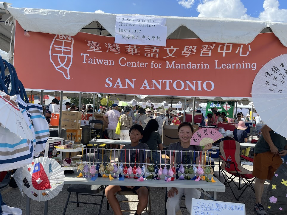 A person sitting at a table with a sign

Description automatically generated