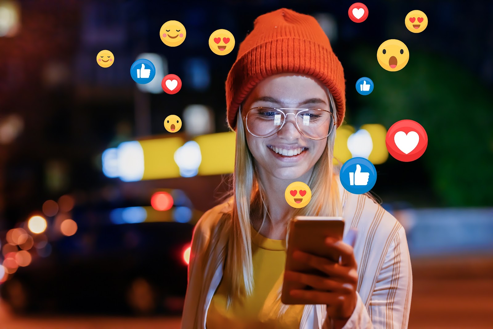 Woman looking at cell phone in her hand with emoji graphics scattered in background